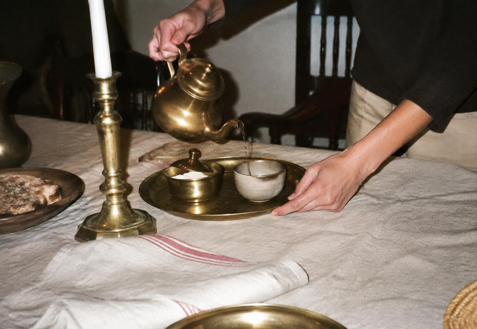 Tea poured over brass and worn linen
