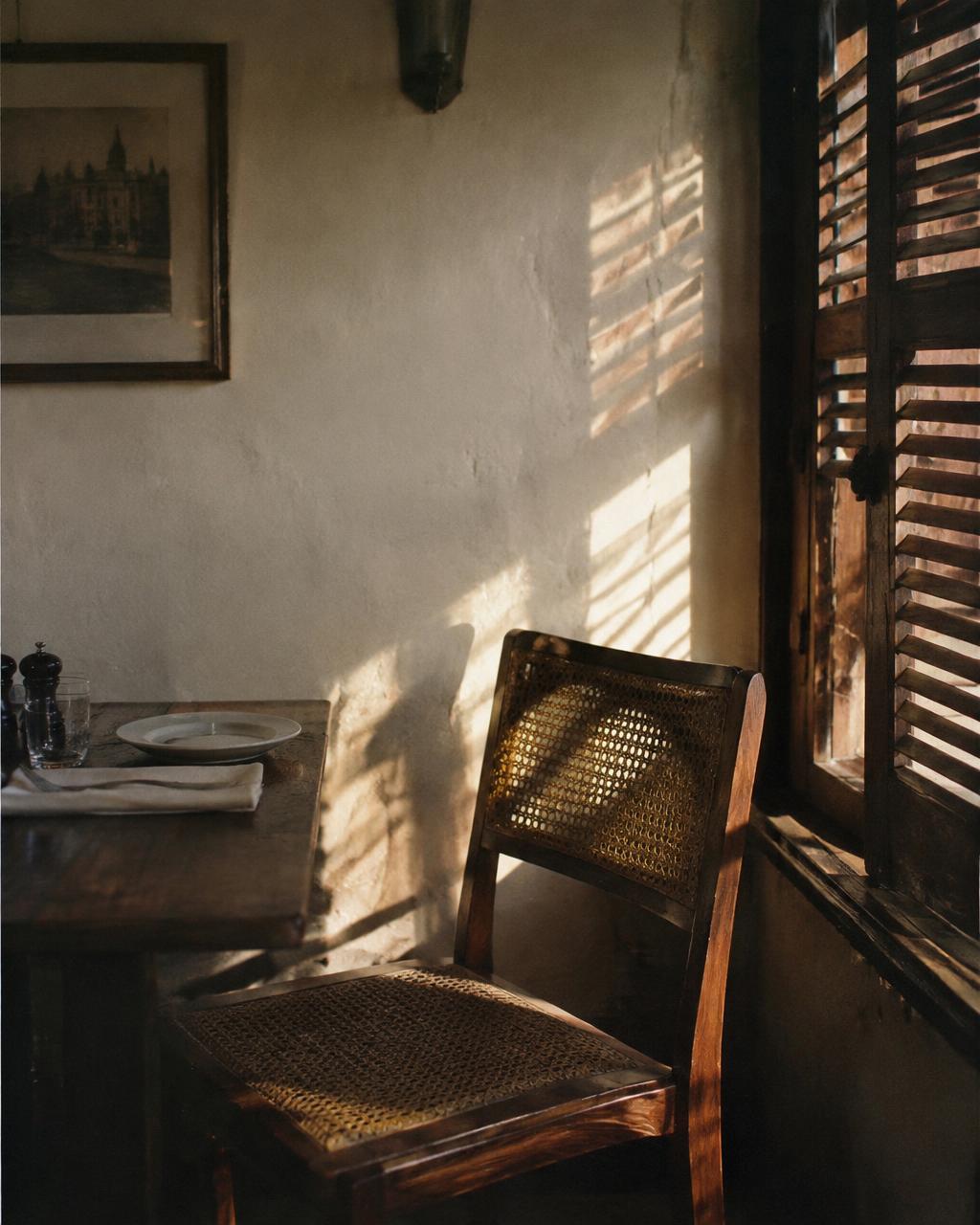 Afternoon shutter light across a cane chair